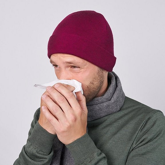 Ein erkälteter Mann mit schwachem Immunsystem putzt sich die Nase.