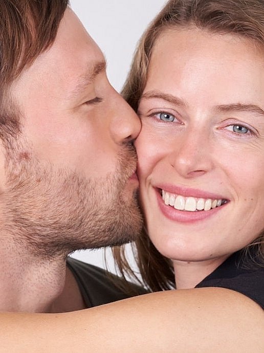 Mann küsst lächelnde Frau beim Date auf die Wange. 