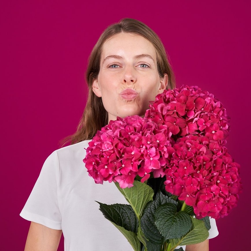 Frau schürzt ihre herpesfreien Lippen und hält einen Blumenstrauß.