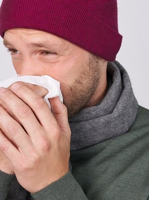 Uomo raffreddato che si soffia il naso.