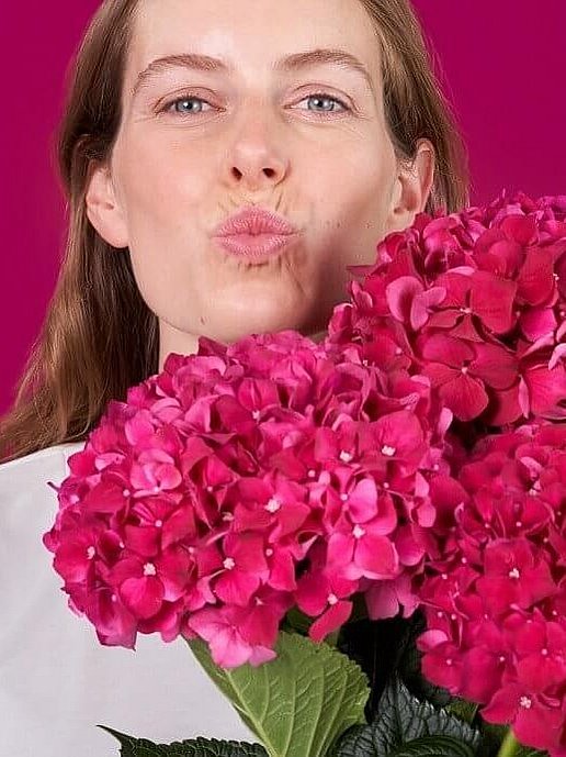 Woman with bouquet of flowers shows puckered lips with no cold sores.