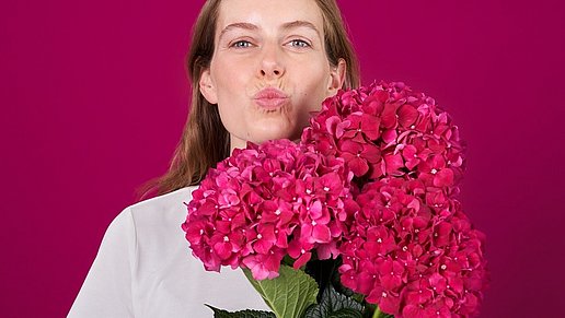 Frau mit Blumenstrauß zeigt herpesfreien Kussmund.
