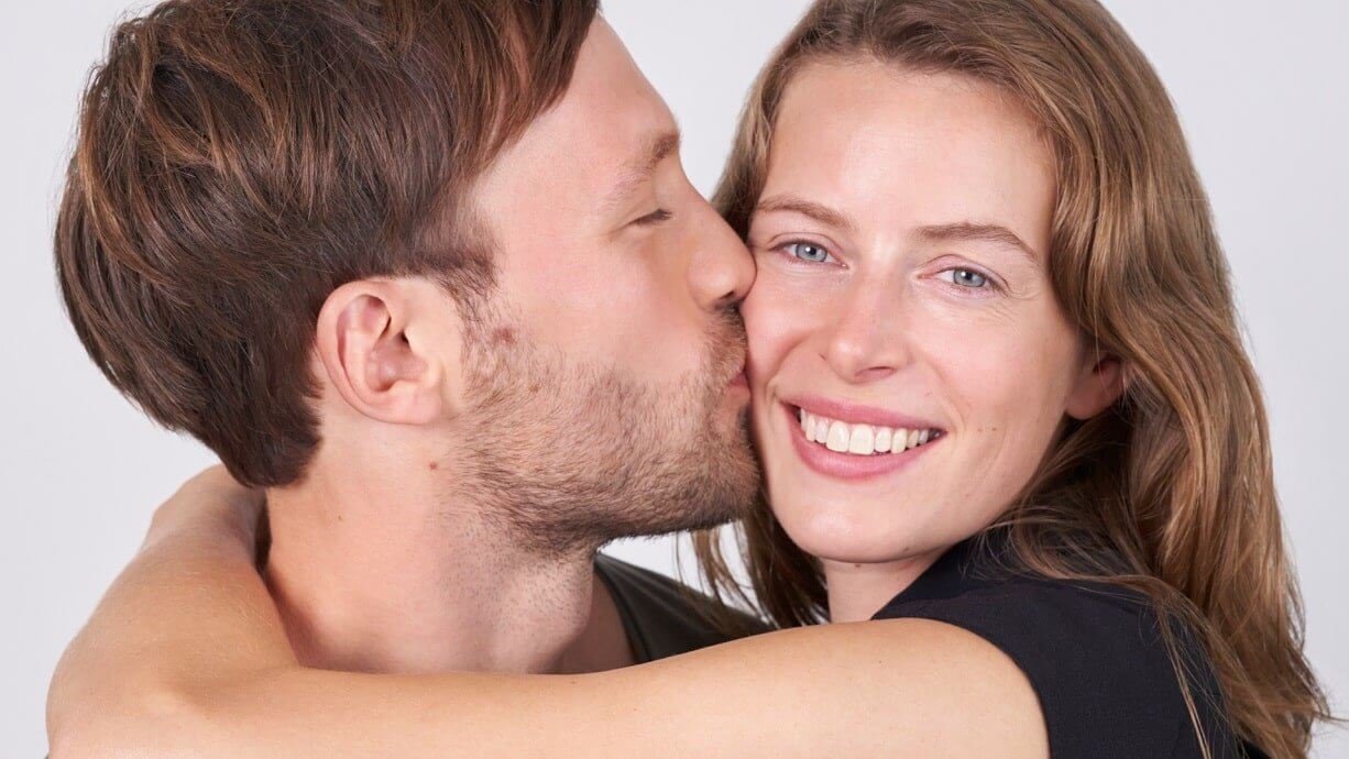 Man kisses smiling woman on the cheek during a date.
